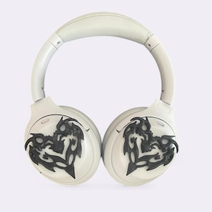 May include: White wireless headphones with black tribal-style designs on the earcups.