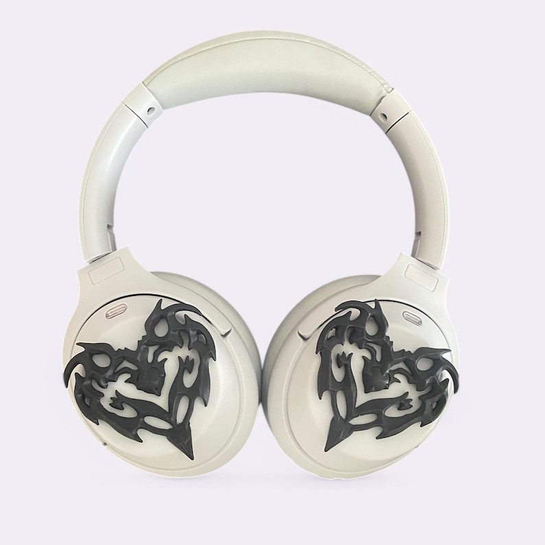 May include: White wireless headphones with black tribal-style designs on the earcups.