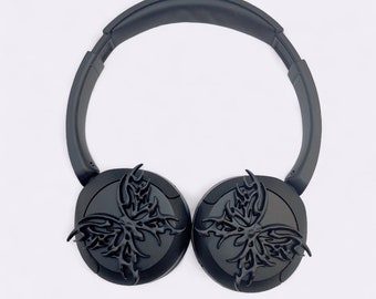 May include: Black headphones with a butterfly design on each earcup. The headphones have a black headband and are made of plastic.