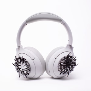 May include: White wireless headphones with a silver, spiky design on each earcup.