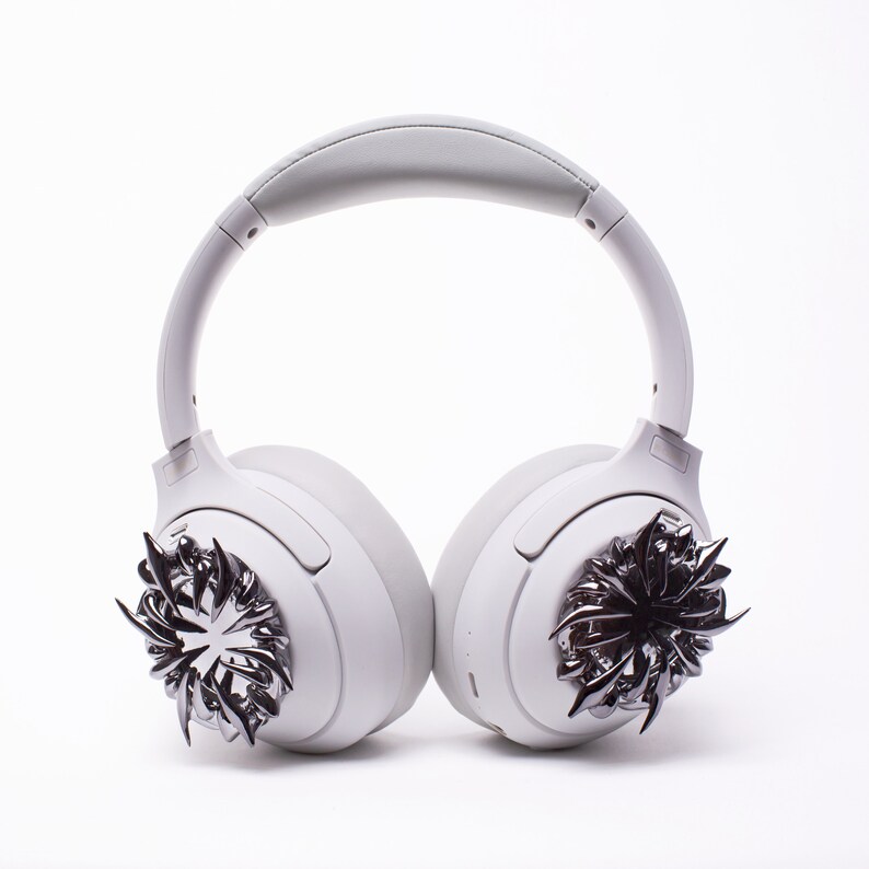 May include: White wireless headphones with a silver, spiky design on each earcup.