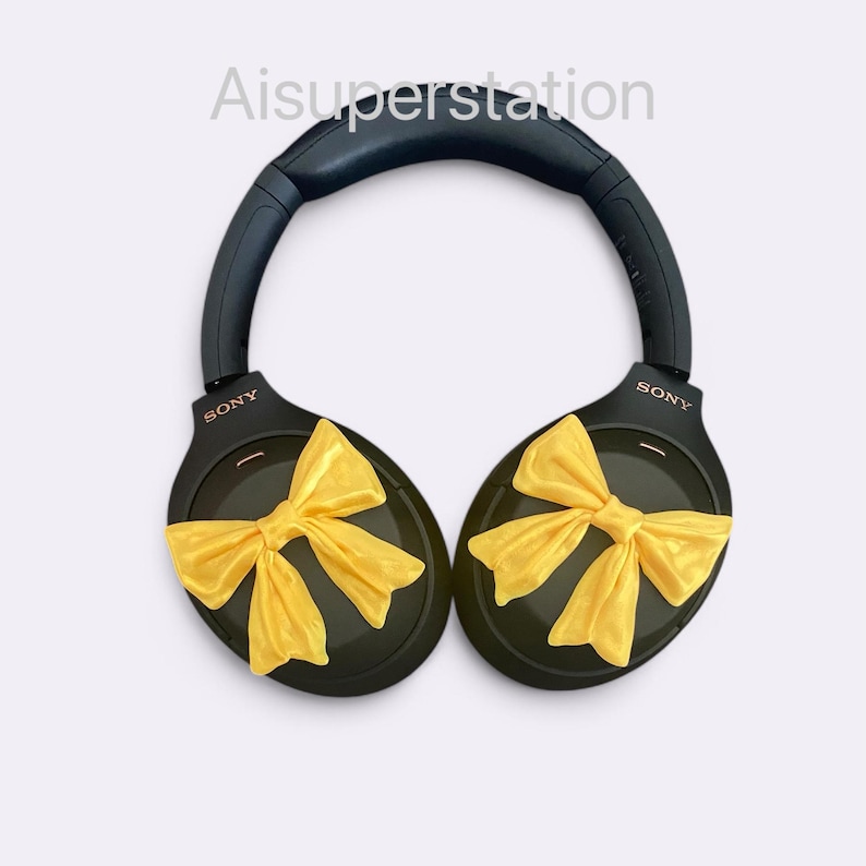 K&ouml;nnte beinhalten: Schwarze Over-Ear-Kopfh&ouml;rer mit gelben Schleifen an jedem Ohrpolster. Die Kopfh&ouml;rer tragen den Schriftzug "SONY" auf jedem Ohrpolster.