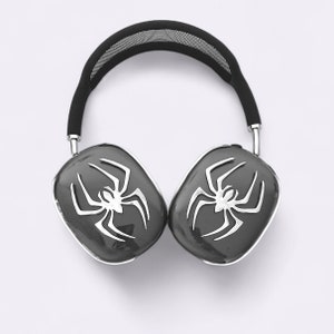 Może przedstawiać: Czarne słuchawki z wzorem pająka na każdym nauszniku. Słuchawki mają czarne siateczkowe pałąk.