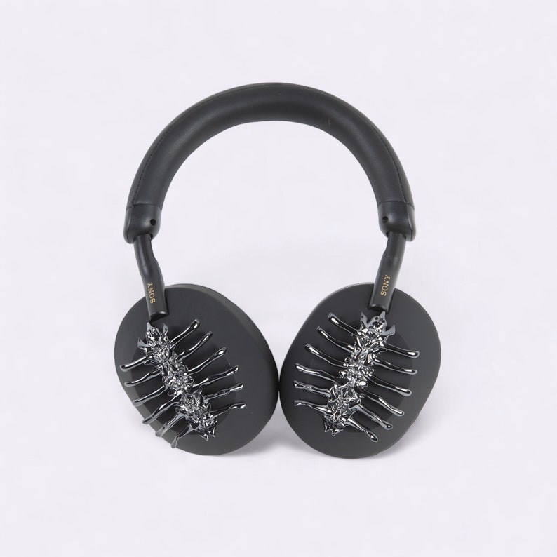 May include: Black over-ear headphones with a silver and black decorative design on the earcups. The headphones have the word "SONY" written on the side.