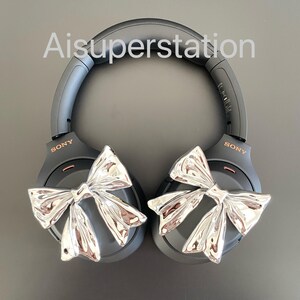 Pu&ograve; includere: Cuffie over-ear nere con dettagli a fiocco argentato. Le cuffie hanno la scritta "SONY" stampata su ogni padiglione.