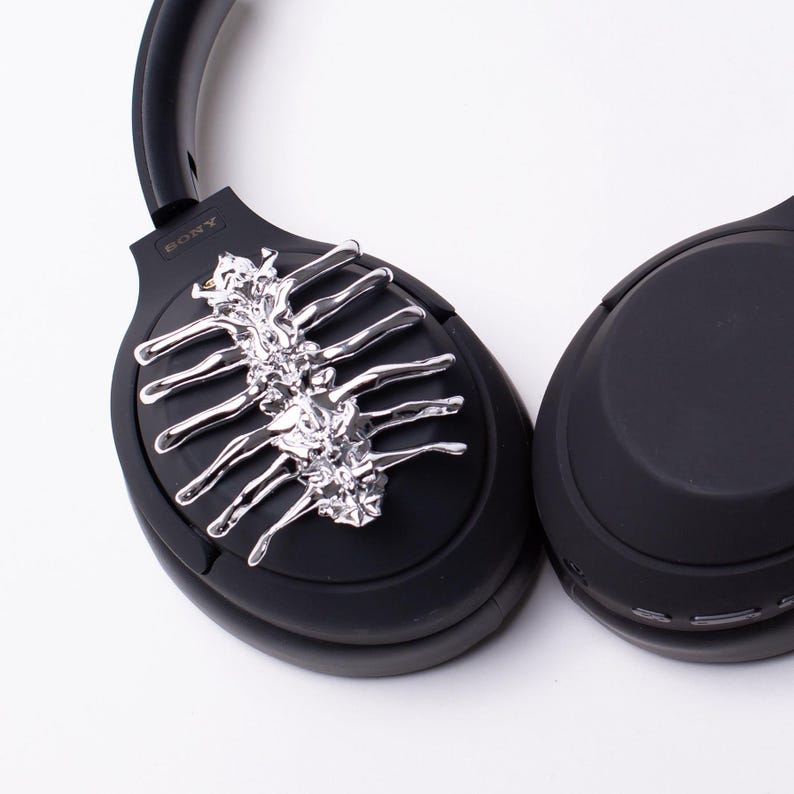 May include: Black headphones with a silver skeletal design on one earcup. The headphones have the word "SONY" printed on the side.
