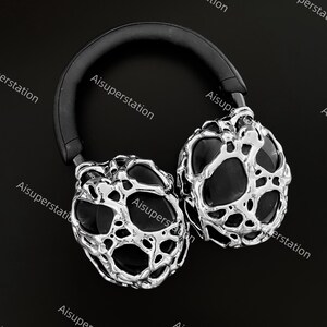 May include: Silver headphones with a black headband and a unique, textured, organic design. The headphones have a futuristic, modern look.