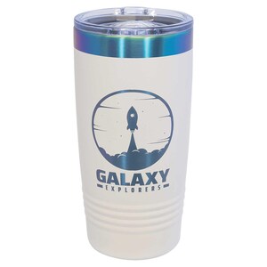 Peut inclure: Un gobelet isotherme blanc avec un couvercle transparent et une bordure irisée. Le gobelet présente un graphisme bleu d'une fusée décollant d'un nuage, avec les mots "GALAXY EXPLORERS" en dessous. Le gobelet est conçu pour contenir environ 590 ml.