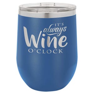 May include: A blue insulated wine tumbler with a silver rim and lid. The tumbler features the white text "It's always Wine O'Clock" in a stylized font. The tumbler is designed to keep beverages at the desired temperature.
