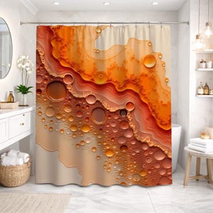 Peut inclure: Rideau de douche avec un motif abstrait aux tons orange, marron et beige. Le design comprend des formes circulaires en forme de bulles, créant un aspect texturé et fluide. Le rideau est suspendu à une tringle argentée dans une salle de bain.