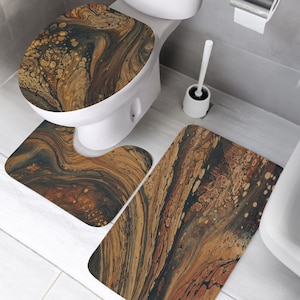 Op de afbeelding: Een driedelige badmatset met een abstract marmerpatroon in bruin, zwart en goud. De set bevat een toiletbrilhoes, een klein matje voor voor de toilet en een groter matje voor de vloer.