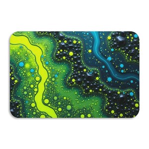 Op de afbeelding: Een rechthoekige muismat met een abstract ontwerp. Het patroon heeft vloeiende lijnen en gespikkelde texturen in tinten groen, geel en blauw, waardoor een dynamisch en kleurrijk visueel effect ontstaat. Het ontwerp lijkt op een close-up van een vloeistofoppervlak.