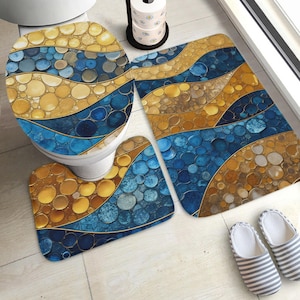 May include: A bathroom set featuring a toilet seat cover, two rugs, and a toilet seat rug. The set has a blue, gold, and brown stone-like pattern. The rugs are rectangular and kidney-shaped. A roll of toilet paper and a pair of striped slippers are also visible.