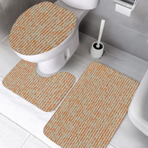 Peut inclure: Un ensemble de trois tapis de salle de bain comprenant une housse de couvercle de toilette, un tapis de contour en U et un tapis de bain rectangulaire. Chaque pièce présente un motif à rayures verticales orange, beige et gris foncé.