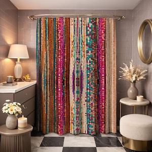 May include: A vibrant beaded shower curtain with vertical stripes in teal, orange, pink, and cream. The curtain hangs from a gold-coloured rod in a bathroom setting. The bathroom has a grey tiled wall, a round gold mirror, and a small side table.