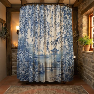 Pode incluir: Cortina de duche azul e branca com uma ilustração de um jardim japonês, incluindo uma pagoda, uma ponte e ramos de salgueiro chorão. A cortina tem um fundo claro e um design artístico detalhado.