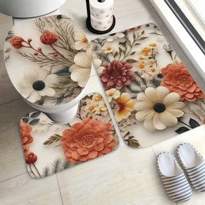 May include: A bathroom set featuring a toilet lid cover, a U-shaped contour rug, and a rectangular bath mat, all decorated with a floral pattern of cream, orange, and dark red flowers, along with green foliage on a light cream background.