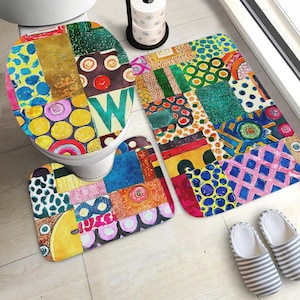 May include: A bathroom set featuring a toilet seat cover, a rectangular bath mat, and a contour rug, all decorated with a vibrant, multi-colored patchwork pattern of geometric shapes, circles, and abstract designs in shades of blue, yellow, and red.