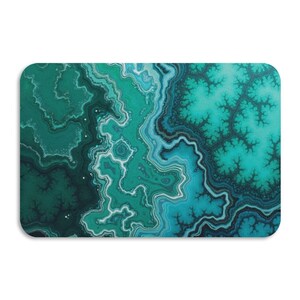 Op de afbeelding: Een rechthoekige decoratieve mat met een wervelend abstract ontwerp in tinten teal, turquoise en donkergroen. Het patroon lijkt op de adering van een edelsteen, met afgeronde hoeken en een witte achtergrond.