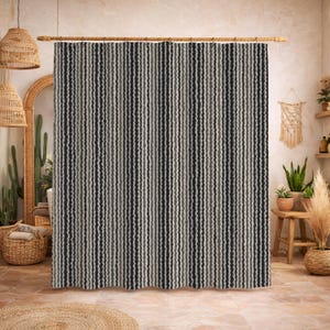 Puede incluir: Una cortina de ducha a rayas con líneas verticales en tonos de negro, gris y blanco. La cortina cuelga de una barra de madera en un baño. El diseño tiene un patrón texturizado y ondulado.