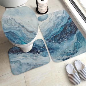 May include: A bathroom set featuring a blue and silver marble pattern. The set comprises a toilet seat cover, a contour rug, and a rectangular bath mat. A pair of striped slippers is placed near the bath mat.