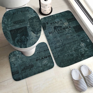 May include: A three-piece bathroom rug set featuring a vintage newspaper print design. The set includes a toilet seat cover, a toilet bowl rug, and a bath mat. The rugs are in shades of blue and grey with black text.