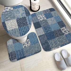 May include: A blue patchwork bathroom set including a toilet seat cover, a contour rug, and a rectangular bath mat. The set features various blue fabric patterns. A pair of striped slippers is next to the bath mat.
