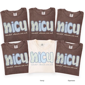 May include: A collection of folded t-shirts in ivory and espresso colors. Each shirt features the word "NICU" in a patchwork design with floral and gingham patterns, along with the text "neonatal intensive care unit".