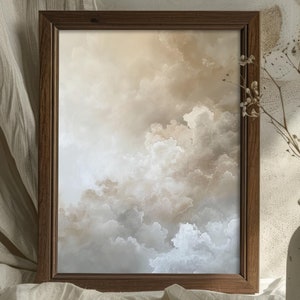 Peut inclure: Une impression encadr&eacute;e d'un ciel nuageux dans des tons de brun et de blanc. Le cadre est en bois fonc&eacute; et repose sur une surface en tissu blanc.