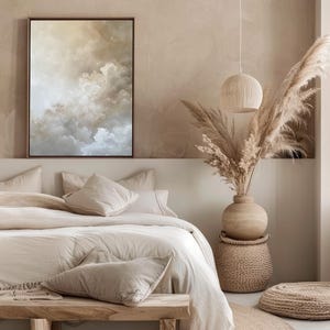 Peut inclure: Une chambre &agrave; coucher beige avec un lit, un banc en bois, une table d'appoint en osier, un vase avec de l'herbe de la pampa s&eacute;ch&eacute;e et un tapis rond en jute. Le lit est recouvert d'une couette blanche et de plusieurs oreillers beiges. Un tableau abstrait encadr&eacute; repr&eacute;sentant des nuages ​​est accroch&eacute; au mur au-dessus du lit.