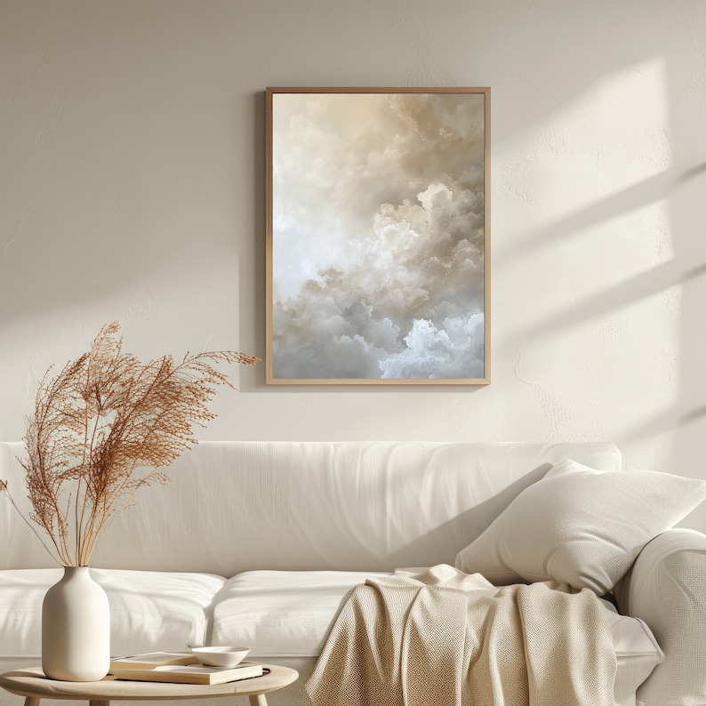 Peut inclure: Une peinture abstraite encadr&eacute;e de nuages dans des tons beige, brun et blanc. La peinture est accroch&eacute;e &agrave; un mur blanc au-dessus d'un canap&eacute; blanc avec une couverture.