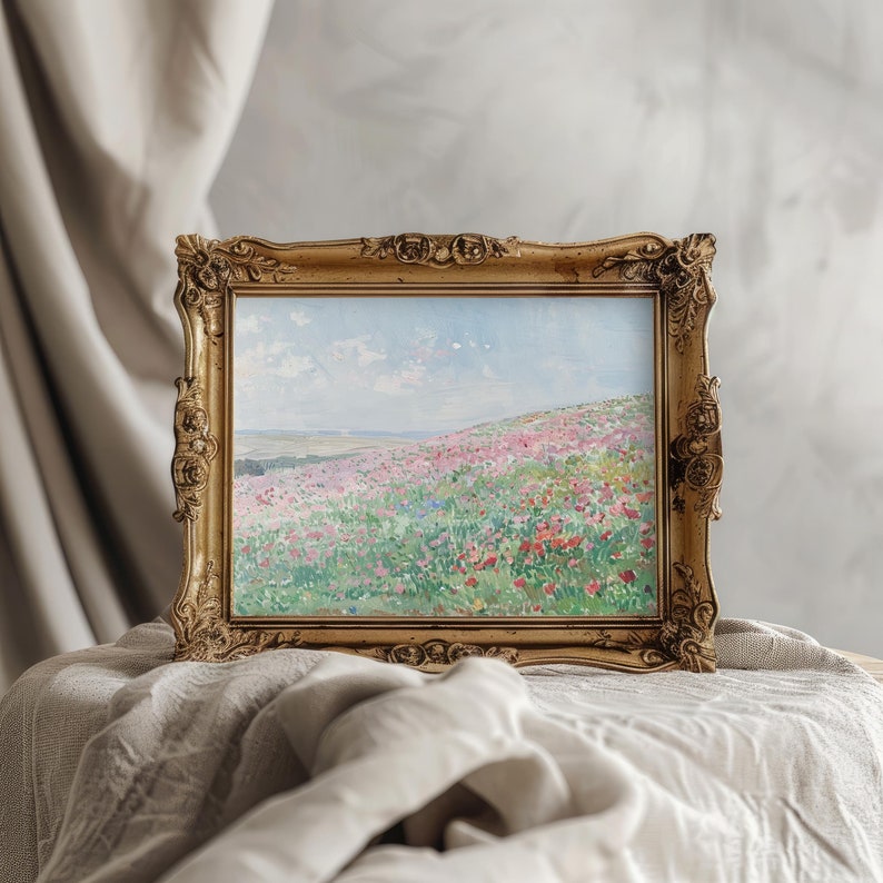 May include: A framed painting of a field of wildflowers in shades of pink, purple, and white. The field is set against a blue sky with white clouds. The painting is in a gold frame with ornate details.