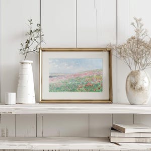 May include: A framed painting of a field of wildflowers in shades of pink, purple, and white. The painting is set against a backdrop of a blue sky with fluffy clouds. The frame is gold and has a simple design.