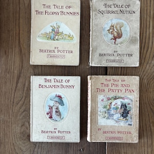 Op de afbeelding: Vier vintage kinderboeken van Beatrix Potter worden getoond. Titels zijn onder meer "The Tale of the Flopsy Bunnies", "The Tale of Squirrel Nutkin", "The Tale of Benjamin Bunny" en "The Tale of the Pie and the Patty Pan". De covers zijn geïllustreerd en versleten.
