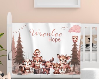May include: A white baby blanket with a pink cloud and a brown owl. The blanket features a woodland theme with a squirrel, deer, and a bird. The text "Wrenlee Hope" is printed in pink on the blanket.