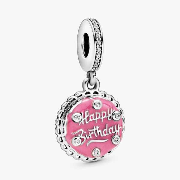Peut inclure: Un charm en argent avec un motif de gâteau en émail rose. Le charm porte l'inscription "Happy Birthday" en écriture cursive et est orné de cristaux transparents. La boucle supérieure est également ornée de cristaux.