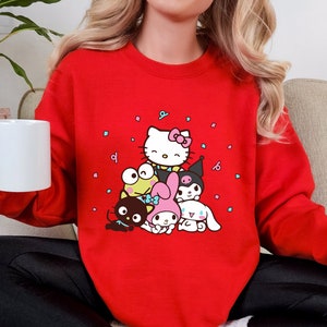 May include: A red sweatshirt with a graphic print of Hello Kitty and her friends. The characters are surrounded by confetti.