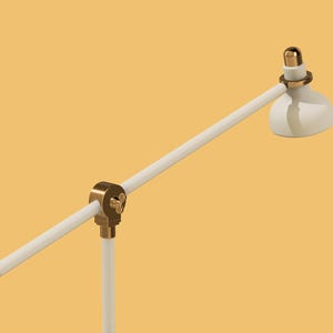 May include: A white desk lamp with a gold-colored base and adjustable arm. The lamp has a white shade.