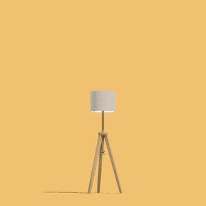 May include: A white lampshade with a wooden tripod stand. The lamp is on a yellow background.
