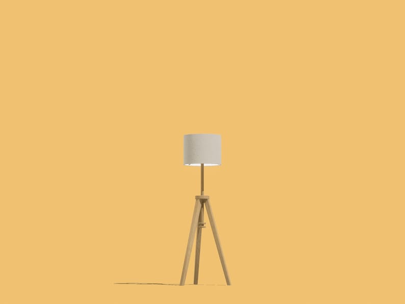 May include: A white lampshade with a wooden tripod stand. The lamp is on a yellow background.