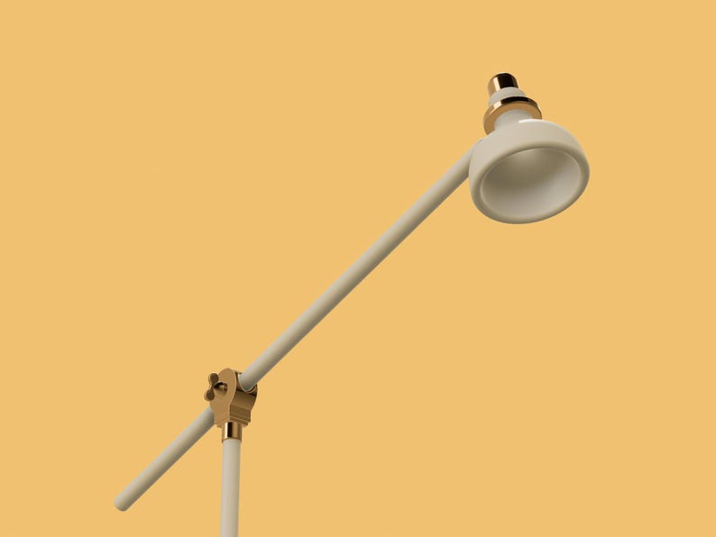 May include: A white desk lamp with a gold base and a white shade. The lamp is adjustable and can be positioned in different directions.