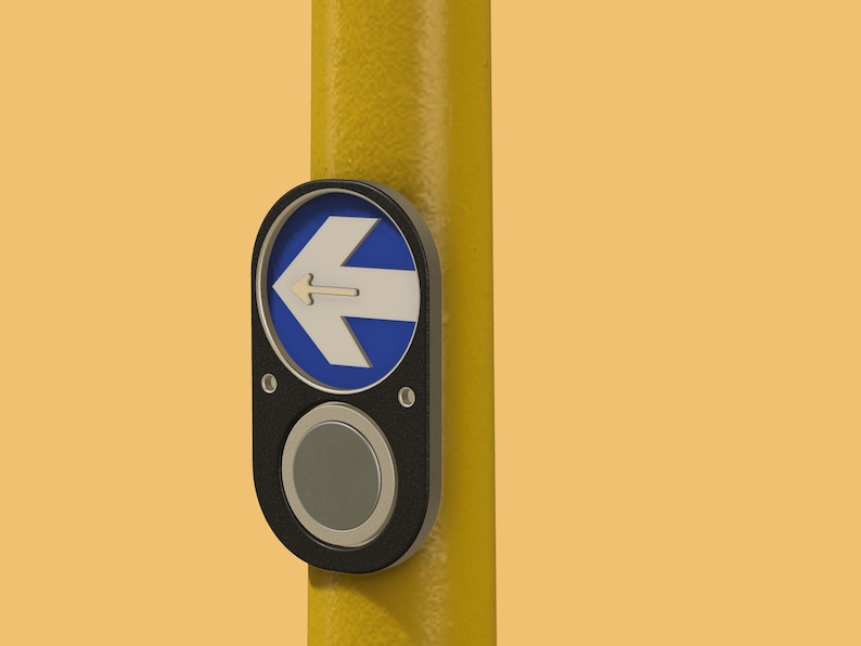 May include: A black button with a white arrow pointing to the left, mounted on a yellow pole. The button is labeled with a blue circle and a white arrow.