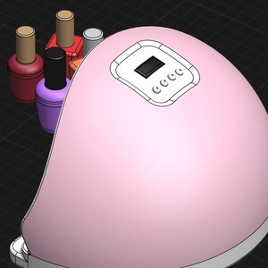 Op de afbeelding: Een roze nagellamp met een digitale timer en een doorzichtig deksel. Vier flesjes nagellak zijn zichtbaar in de lamp.