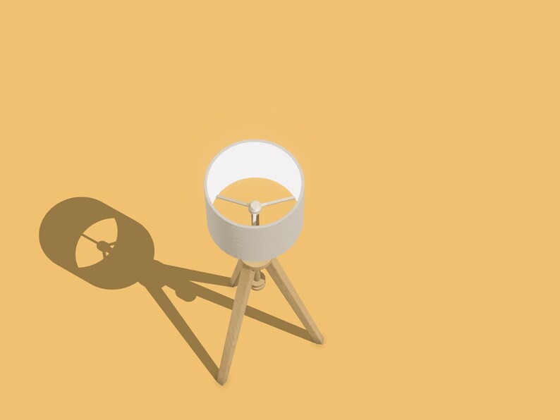 May include: A white lampshade with a wooden tripod stand casts a shadow on a yellow surface.