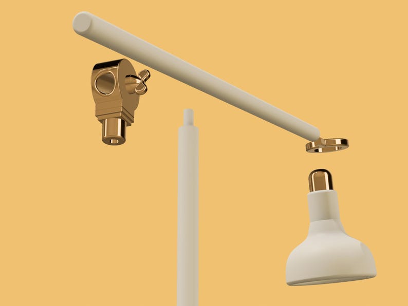 May include: A white desk lamp with a gold-colored base and a white shade. The lamp is disassembled, showing the individual parts.