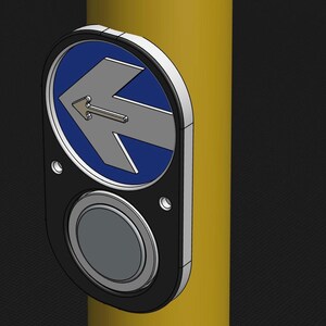 May include: A black and silver push button with a blue and silver arrow pointing left. The button is mounted on a yellow pole.