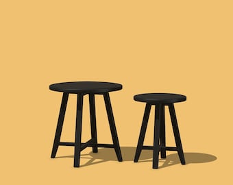 May include: Two black wooden stools with round seats and three-legged bases stand against a yellow background. The larger stool is taller than the smaller one. The stools are simple in design and appear to be made of solid wood.
