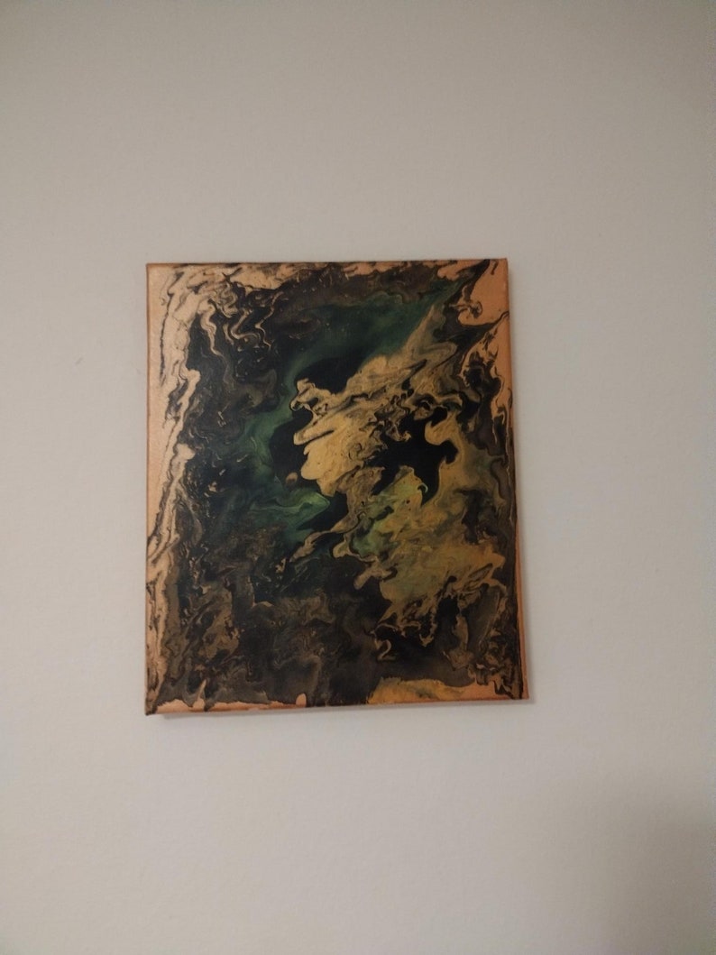 以下が含まれることがあります： 黒、緑、金色の絵の具が渦巻く、キャンバスに描かれた抽象画です。