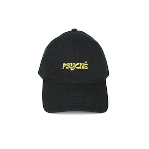Könnte beinhalten: Eine schwarze Baseballkappe mit einem gelben gestickten Logo, auf dem "PSYCHÉ" steht.
