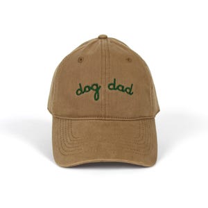 May include: A brown baseball cap with green embroidered text that reads "dog dad".